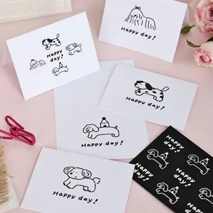 Detalle de tarjetas de felicitación blancas con dibujos de perros y texto Happy day