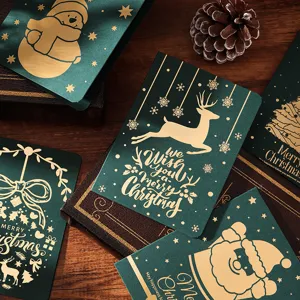 Gros plan sur des cartes de Noël vert foncé avec motif de renne en dorure à l'or