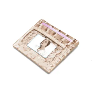 Dettaglio macro di un porta carte beige da donna con stampa coccodrillo e vano ID.