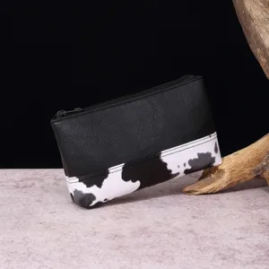 Detalle de neceser de cuero con estampado de vaca y cierre de cremallera