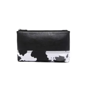 Vista detallada del bolso de cuero sintético negro con estampado de vaca y cremallera metálica
