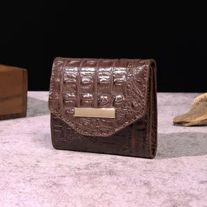 Detalle de una cartera triple para mujer en cuero marrón con relieve de cocodrilo