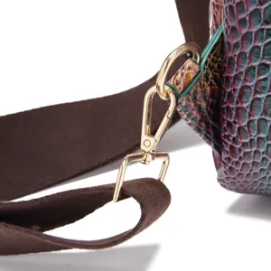 Primer plano del cierre metálico dorado de un bolso vintage con elegante patrón de cocodrilo
