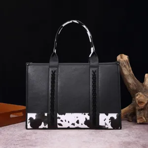 Detalle de bolso tote retro de cuero negro con detalles de estampado de vaca y trenzado.