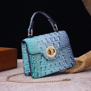 Detail of a teal crocodile-embossed retro handbag with gold-tone metal lock and chain strap.