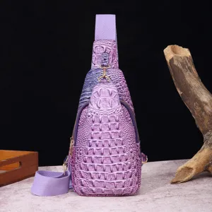 Detalle frontal de bolso bandolera morado con relieve de cocodrilo y correa ancha