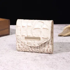 Detalle de billetera para mujer con estampado de cocodrilo en crema y cierre dorado