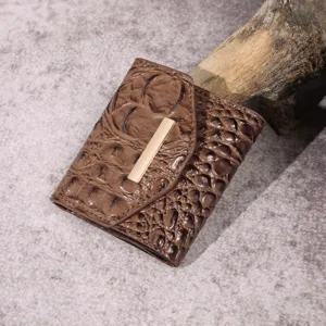 Primer plano de cartera para mujer con textura de cocodrilo marrón y hebilla dorada
