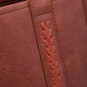Detalle de cerca de la textura trenzada y las costuras de un bolso de cuero marrón vintage.