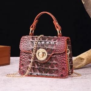 Detailed view of crocodile embossed leather handbag with gold chain strap