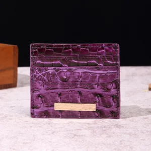 Primo piano di un portacarte in pelle viola con trama a coccodrillo e dettaglio in metallo