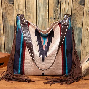 Close-up of vintage canvas shoulder bag with ethnic patterns and long brown tassels.