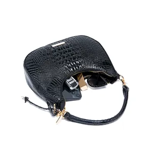 Vista interna dettagliata della borsa hobo nera a coccodrillo con oggetti quotidiani.