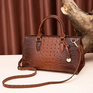 Vista detallada del bolso retro marrón con grabado de cocodrilo y herrajes dorados