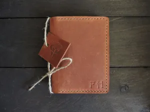 Close-up of vintage brown Crazy Horse leather wallet with embossed initials.