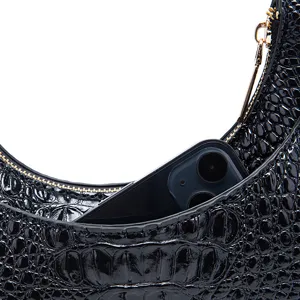 Dettaglio borsa sottobraccio nera in coccodrillo che mostra lo spazio per lo smartphone.