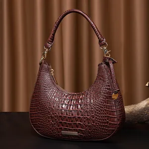 Dettaglio di una borsa sottobraccio marrone vintage con motivo a coccodrillo e hardware oro