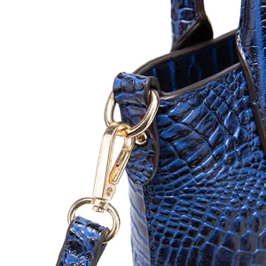 Primer plano detallado de un bolso azul con textura de cocodrilo y cierre metálico dorado