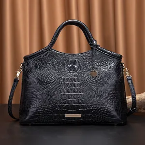 Vista detallada de bolso de mano negro con patrón de cocodrilo y elegantes piezas doradas