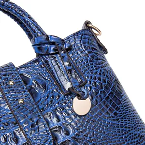 Primer plano de bolso vintage azul con textura cocodrilo y elegante dije de metal.