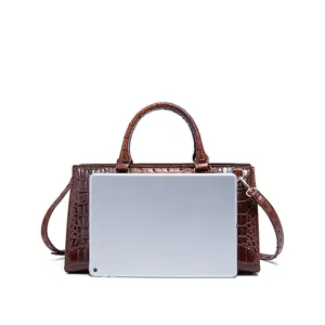 Bolso vintage marrón con grabado de cocodrilo y tableta para comparar tamaño