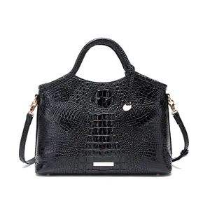 Detalle de bolso de mano en piel grabada de cocodrilo negro con herrajes dorados