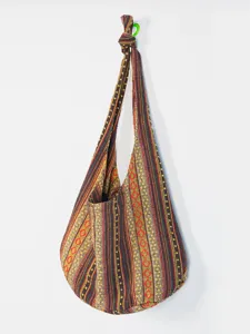 Vista detallada de un bolso hobo vintage de lona tejida de estilo azteca colgado en la pared.