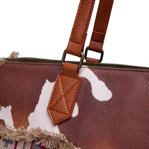 Detailed macro view of bohemian tote bag featuring leather straps and cow print texture