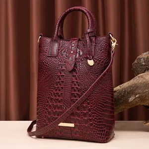 Primer plano de bolso bandolera vintage burdeos con estampado de cocodrilo y oro
