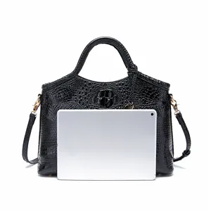 Elegante bolso vintage negro con patrón de cocodrilo y tableta para referencia de tamaño