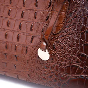 Detalle de bolso bandolera vintage marrón con patrón de piel de cocodrilo en relieve
