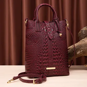 Bolso de mano vintage burdeos con grabado de cocodrilo y detalles en dorado.