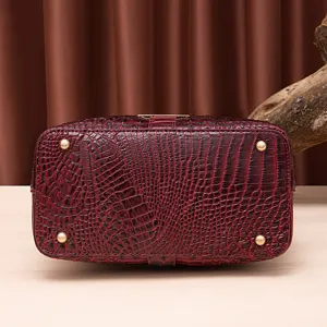 Vista inferior del bolso vintage burdeos con estampado de cocodrilo y pies metálicos