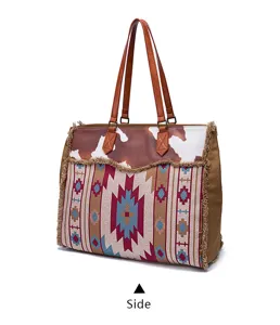 Detailed view of large vintage bohemian canvas tote bag with cow print and fringe.