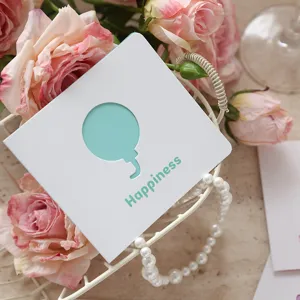 Dettaglio biglietto augurale bianco quadrato con scritta Happiness e intaglio a palloncino