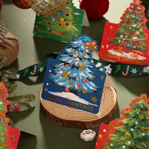 Close-up of Christmas tree shaped greeting cards with gold foil stamping text