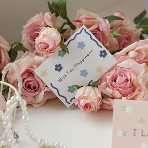 Detailed view of a white floral greeting card with Wish You Happiness text and pink roses.