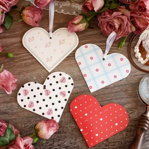 Nahaufnahme von vier sortierten herzförmigen Geschenkkarten mit eleganten weißen Bändern