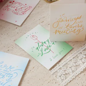Primer plano de tarjetas de felicitación minimalistas con frases románticas a mano.
