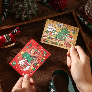 Detailopname van een hand die schattige kerstkaarten met feestelijke stripfiguren vasthoudt.