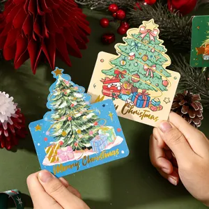 Detailed view of gold foil Merry Christmas tree gift message cards being held by hands