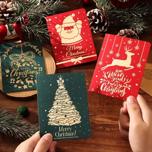 Gros plan de mains tenant diverses cartes de Noël rétro rouges et vertes en feuille d'or