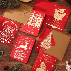 Detailansicht roter Weihnachtskarten mit Goldfolie und Kraftumschlägen auf Holzhintergrund.