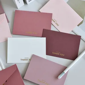Dettaglio di biglietti minimalisti rosa e bordeaux con scritte Thank You in oro