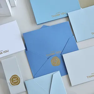 Dettaglio di biglietti di ringraziamento in lamina d'oro e buste blu eleganti con sigilli