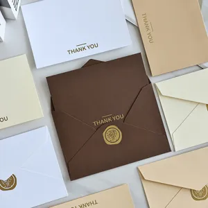Dettaglio di eleganti biglietti di ringraziamento in lamina d'oro e buste dai toni neutri.