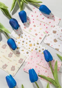 Detalle de tarjetas de felicitación de animales con texto en pan de oro y tulipanes azules