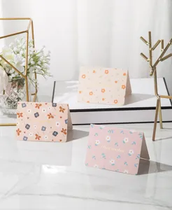 Close-up of floral greeting cards with gold stamped text in a lifestyle setting.