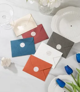 Primer plano de sobres de colores elegantes con sellos de pegatinas florales decorativas.
