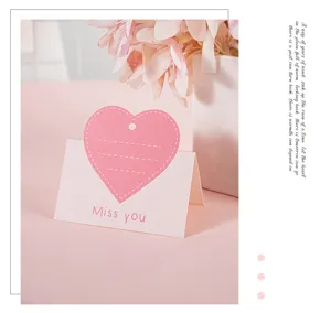 Nahaufnahme einer rosa herzförmigen Grußkarte mit Miss you Text für Geschenkverpackungen